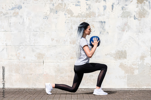 Woman with long braided hair doing fitness workout with a medicine ball. Youth, lifestyle concept