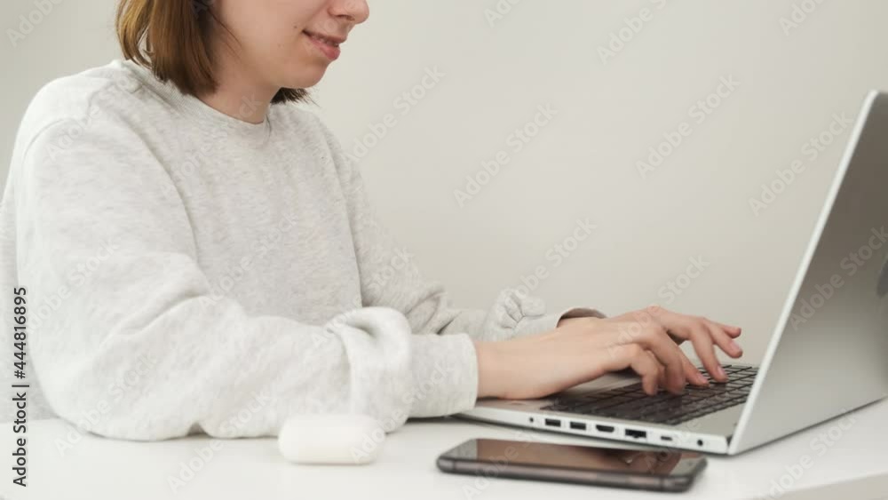Woman puts wireless headphones in the ear and typing on the notebook. Woman puts wireless headphones in the ear and typing on the notebook.