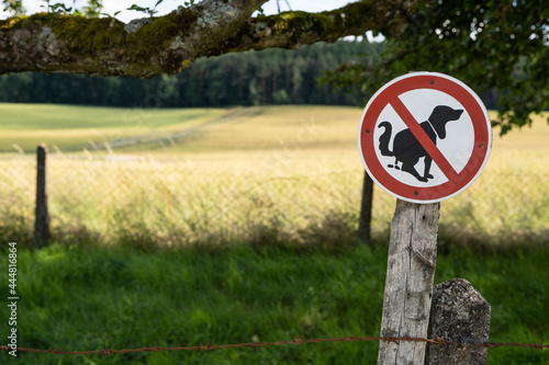 Sign in the landscape with the meaning that dogs are not allowed to make their poop in the meadow