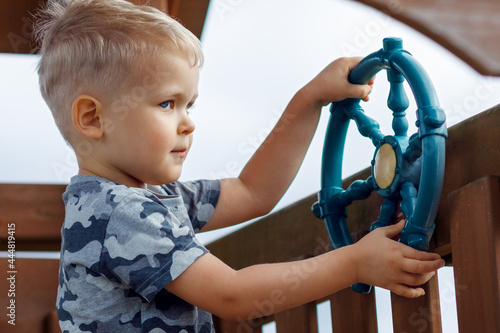 Little boy captain with steering wheel on ship