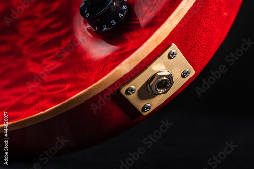 Closeup of a cable input jack of red shiny electric guitar body