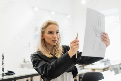 young fashion designer measuring proportions of drawing with pencil © LIGHTFIELD STUDIOS