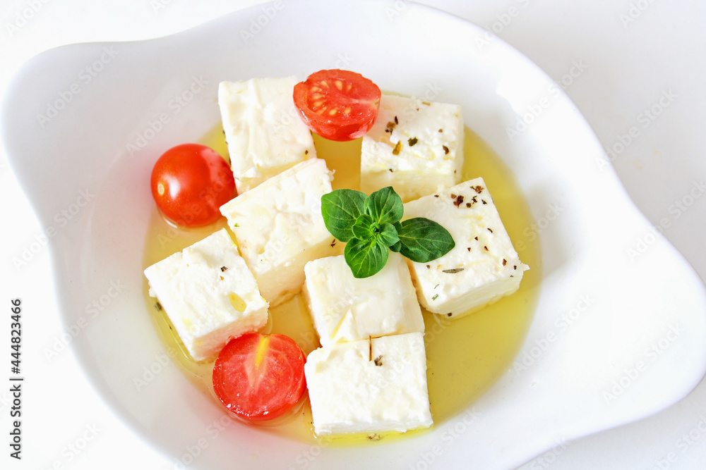 Feta cheese cubes with cherry tomato and olive oil in white bowl Feta cheese cubes with cherry tomato and olive oil in white bowl