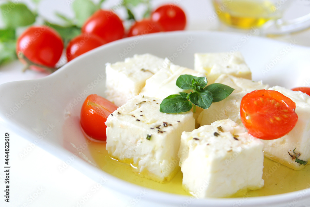 Feta cheese cubes with cherry tomato and olive oil in white bowl Feta cheese cubes with cherry tomato and olive oil in white bowl