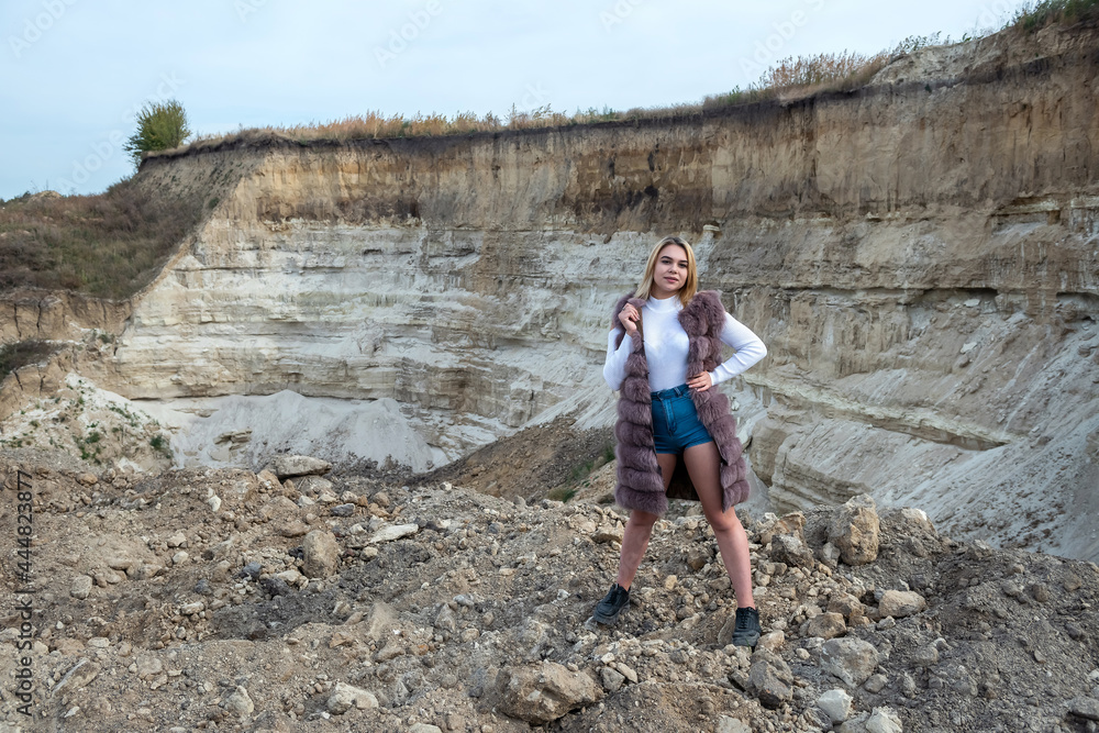 Gorgeous fashion model wear fur coat standing at dry empty sand quarry