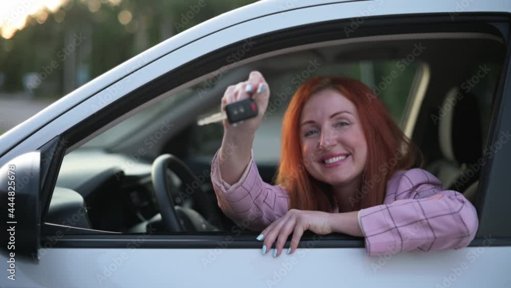 Happy young woman driver sits behind wheel of car and shows keys. Happy young woman driver sits behind wheel of car and shows keys.