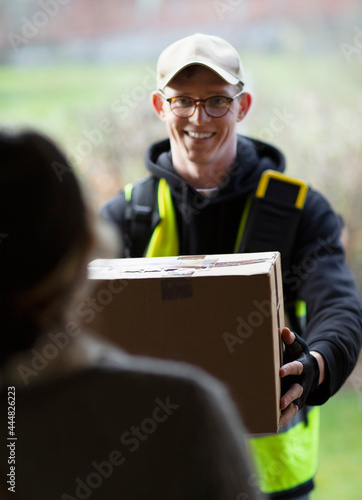 Friendly courier delivering package at front door
