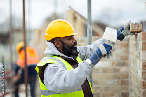 Male construction worker laying bricks at construction site