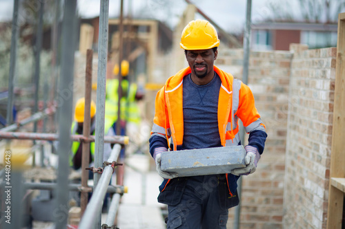 Male construction worker carrying brick at construction site photo