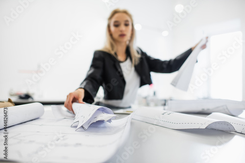 blurred fashion designer working with sewing patterns at workplace