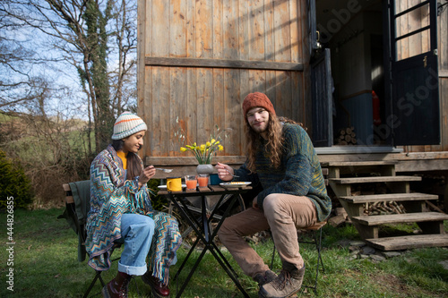 Portrait young couple eating at table outside tiny cabin rental