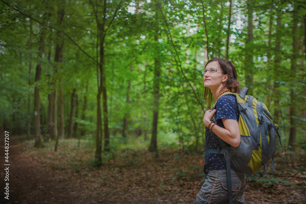 A young woman with a backpack on her back enjoys a hike in the forest. A young woman with a backpack on her back enjoys a hike in the forest.
