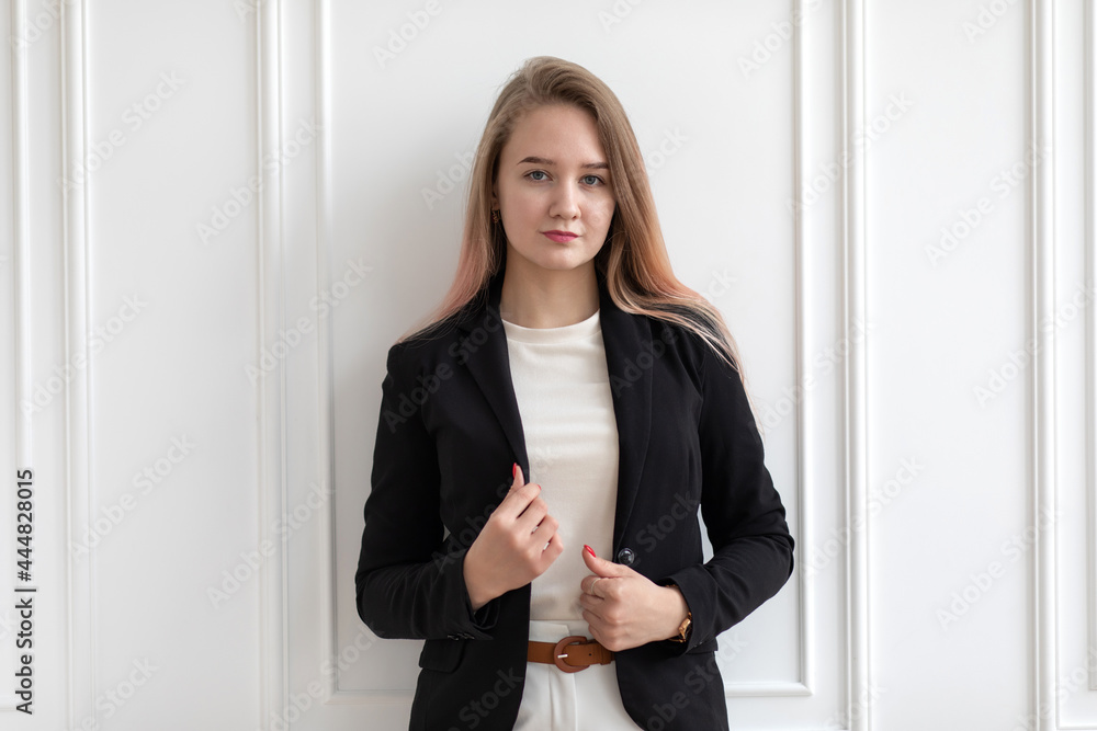 Young beautiful Caucasian woman in casual office clothes standing and holding black jacket, posing. Young beautiful Caucasian woman in casual office clothes standing and holding black jacket, posing.
