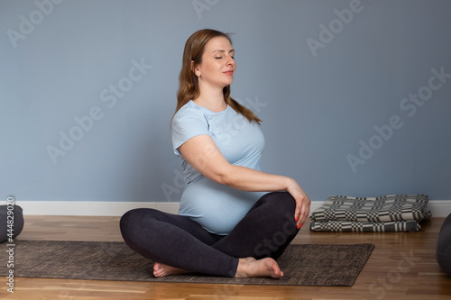 Pregnant caucasian woman sitting on floor in twisted pose stretching © Viktor Koldunov