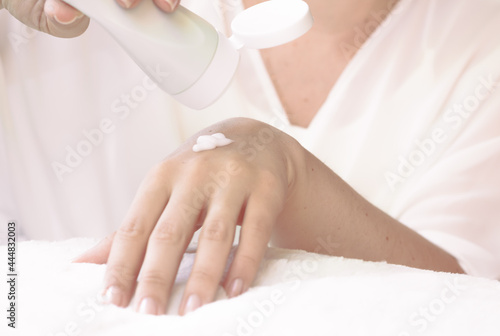 Hands of a young woman applying white moisturizing cream to her skin  on a light background. healthy lifestyle and daily life. Hand cream
