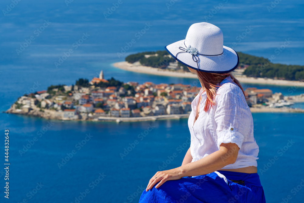 Beautiful tourist woman in a white straw hat on beautiful blue Adriatic Sea and cozy island background. Croatia during summer holiday. Luxury life at holiday at turquoise sea, ocean. Travel concept