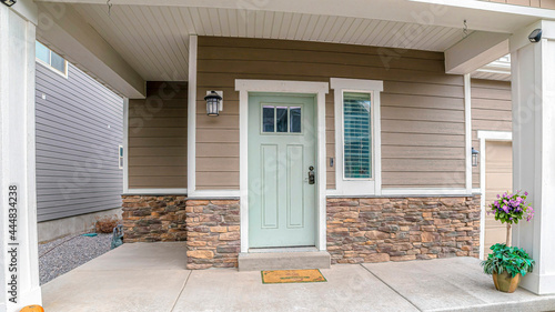 Pano Front door and sidelight against brick wall and wood siding of home with porch