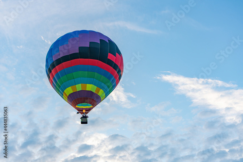 Multicolored hot air balloon on blue cloudy sky background