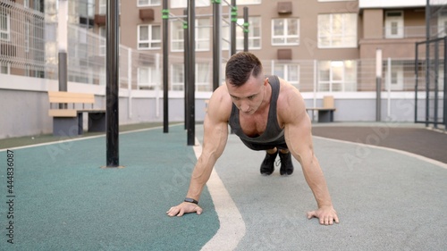 Build muscles in the fresh air. Sport and healthy lifestyle concept. The guy does push-ups on the street on the sports ground. A young man does push-ups on the street on a specialized sports ground
