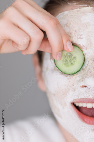 closeup woman with a facial clay mask on laughing and having sli