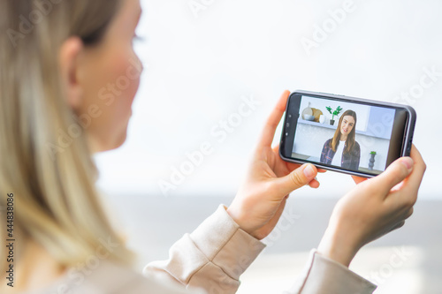 Hands of female student with smartphone makes conference video call on smartphone talks with web tutor, online teacher in remote webcam chat on screen. Distance education class concept