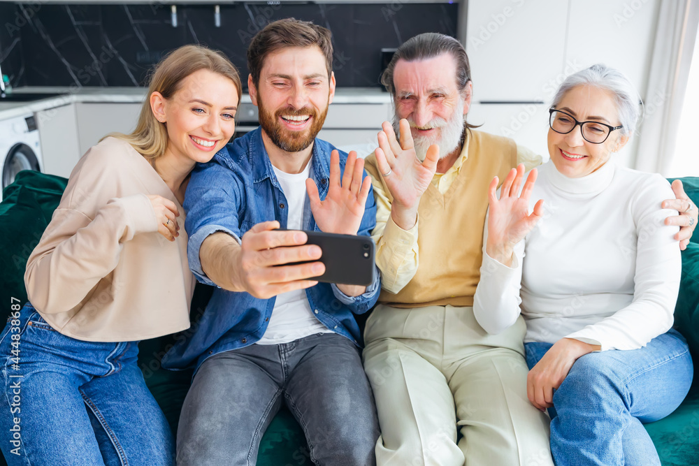 A cheerful family with a small child sitting on the couch, having fun on the Internet, using the application, talk via video link with relatives. A cheerful family with a small child sitting on the couch, having fun on the Internet, using the application, talk via video link with relatives.