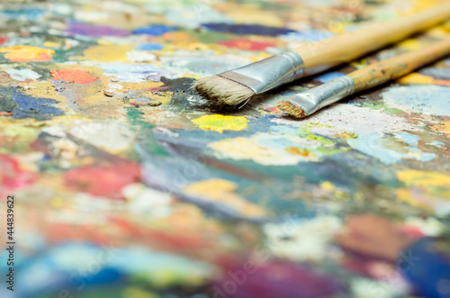 Pincel de pintura al oleo en paleta de colores variados y brillantes. Acrílico multicolor con pincel amarillo, rojo y verde. Arte y artesanías. 