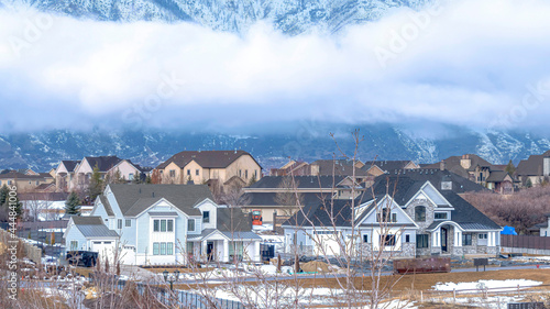 Pano Utah Valley community with towering Wasatch Mountain and dense clouds background