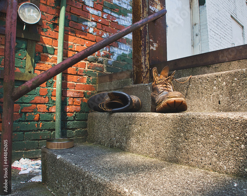 Lonely abandoned work boots on a set of stairs in an alley photo