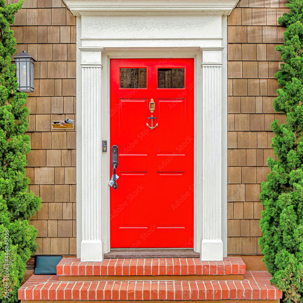 Square Facade of house in Long Beach with vibrant red front door flanked by lush plants