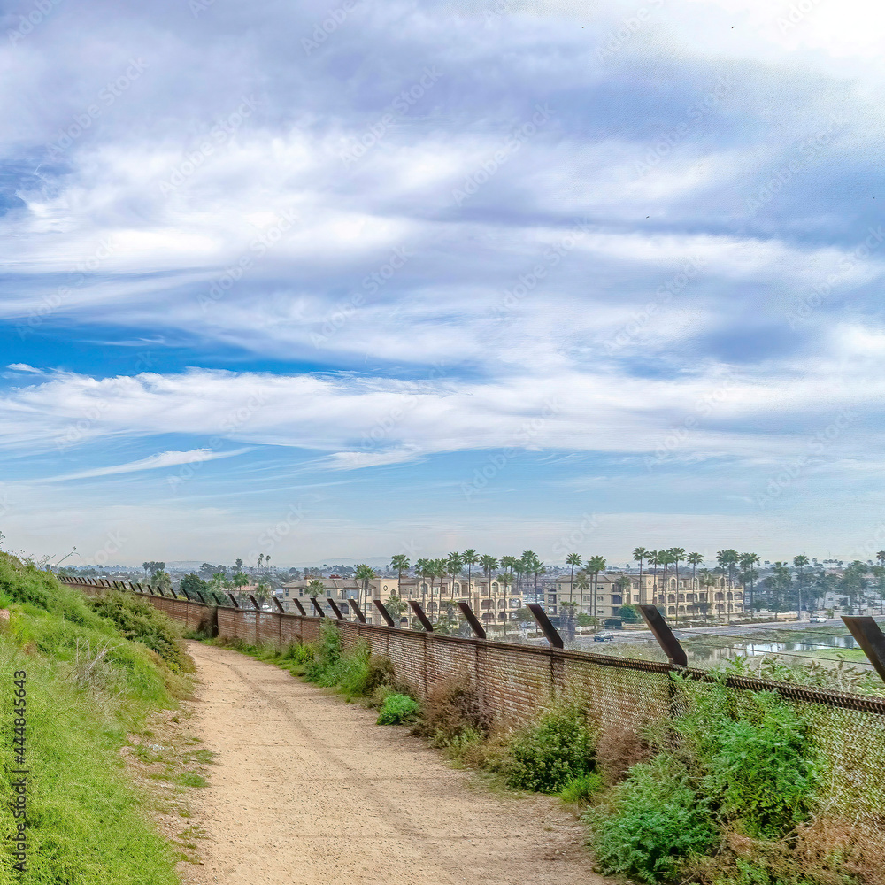 Square Narrow trail pathway under cloudy blue sky in Huntington Beach California