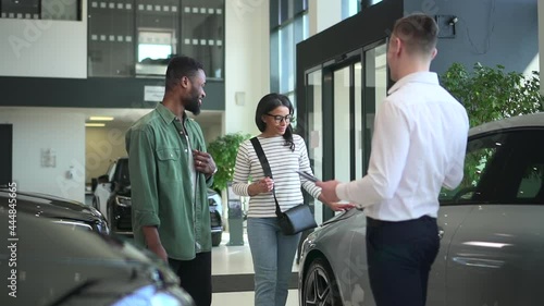 Choosing new automobile couple looks at car with salesman Spbd