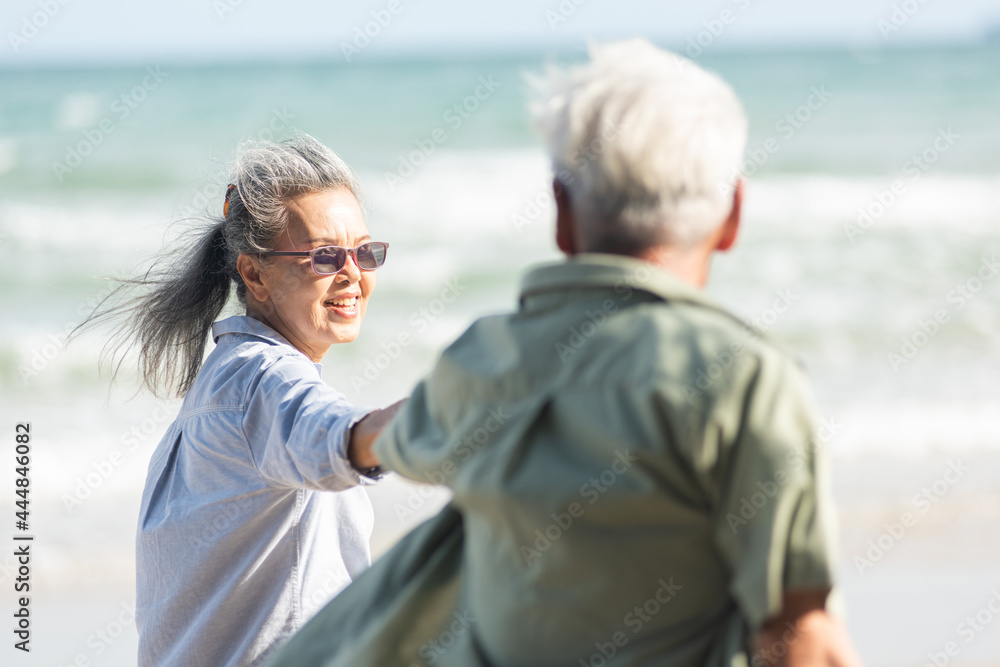 Happy Asian senior man and woman couple holding hands walking to the beach sunny with bright blue sky, Romantic elderly enjoy Travel summer vacation, plan life insurance at retirement couple concept Happy Asian senior man and woman couple holding hands walking to the beach sunny with bright blue sky, Romantic elderly enjoy Travel summer vacation, plan life insurance at retirement couple concept