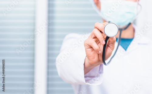 Closeup of doctor man wearing white coat standing holds his stethoscope on hand for listening check up lungs or heart, person showing medical equipment