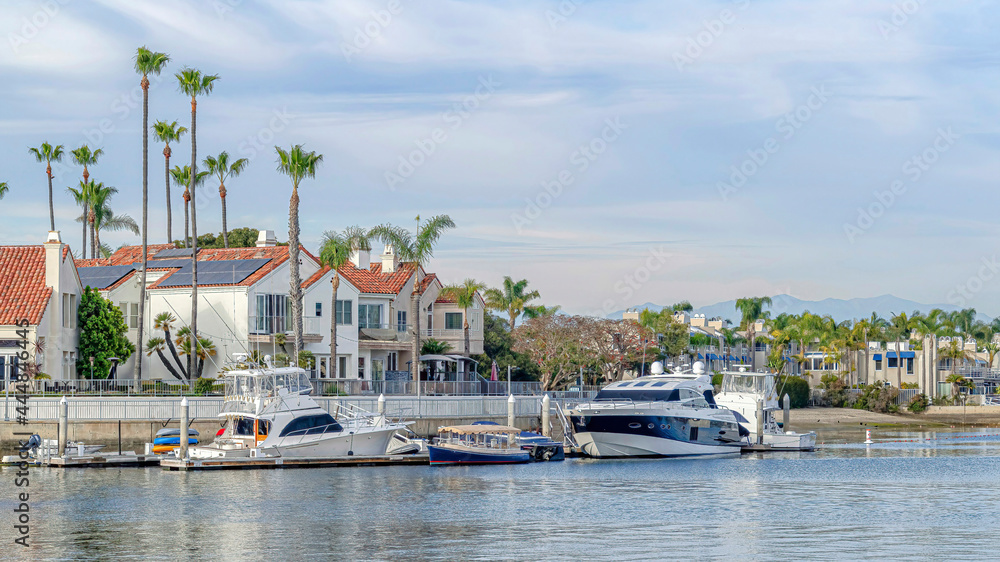 Fototapeta premium Pano Sea and houses with boats and docks against clouds and blue sky background