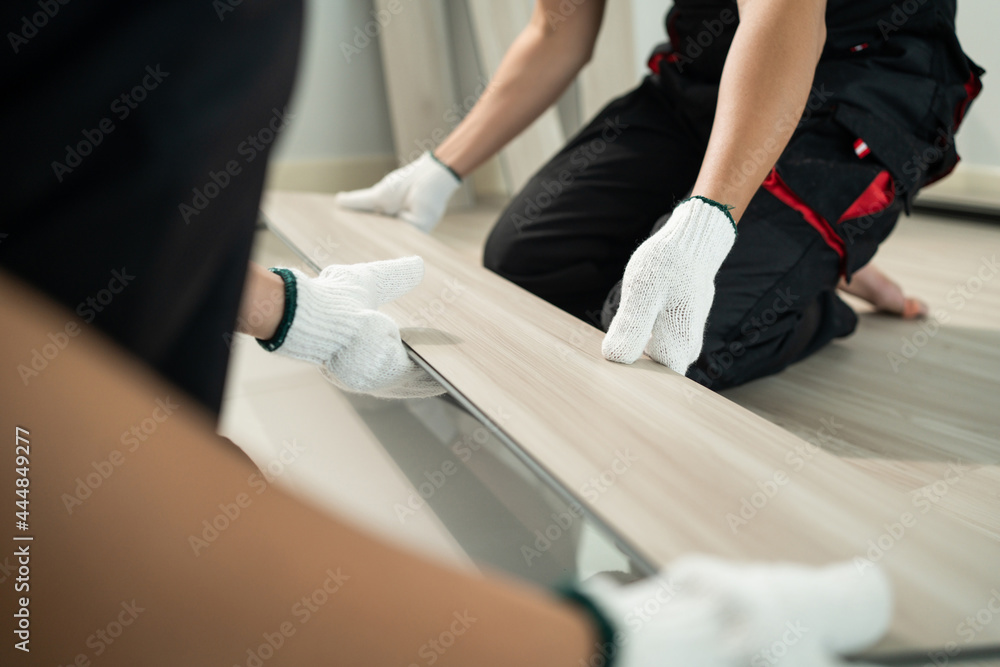 Close-up of Craftsman worker installs laminate board on floor at home. Close-up of Craftsman worker installs laminate board on floor at home.