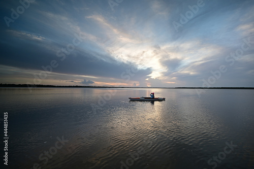 Woman kayaking on Coot Bay in Everglades National Park, Florida at sunset. under dramatic summer cloudscape.