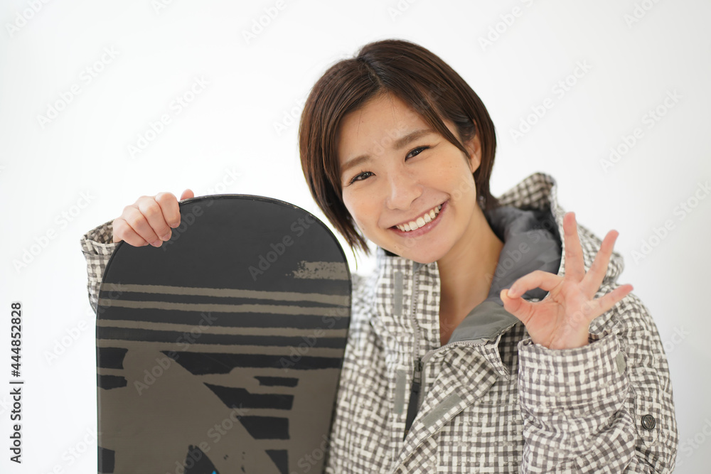 手でマルを作るスノーボードウェアの女性