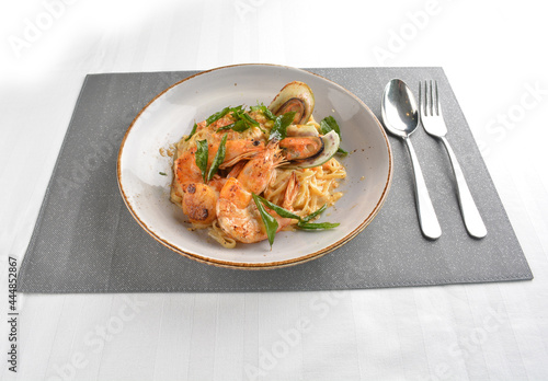 mixed seafood pasta with big tiger prawn, scallop shell clam and muscle in alio olio salted egg yolk paste sauce in white background western halal cuisine 