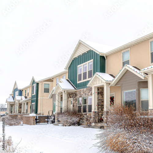 Square Snowy neighborhood with apartment featuring gables entrances and small porches