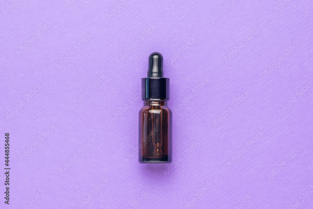 A bottle of medicine made of dark glass on a purple background. Flat lay.