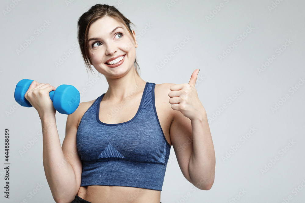 Picture of fit and healthy young woman smiling and holding dumbbelsl to shoulder. Sport and people concept. Picture of fit and healthy young woman smiling and holding dumbbelsl to shoulder. Sport and people concept.