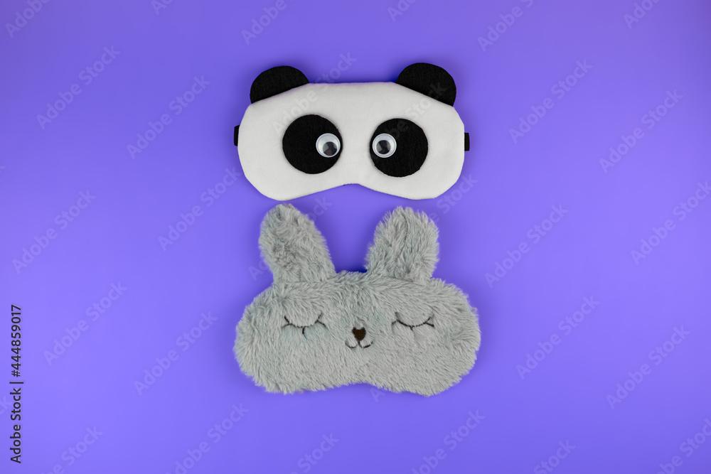 Sleep masks with a panda and rabbit face. Cute sleep masks on a purple background, top view. Accessories for a comfortable sleep Sleep masks with a panda and rabbit face. Cute sleep masks on a purple background, top view. Accessories for a comfortable sleep