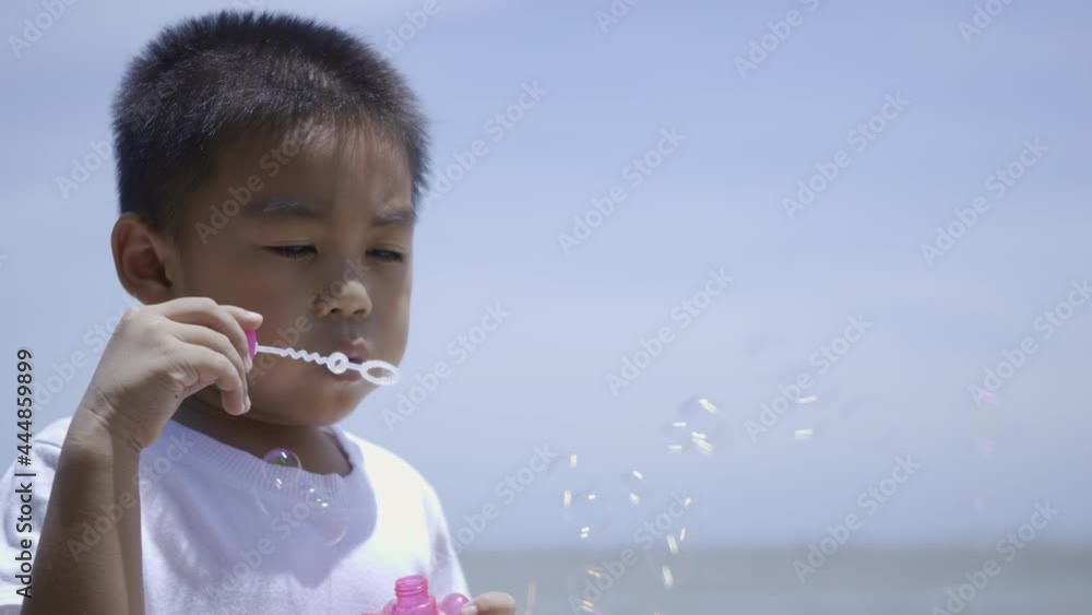 Happy little child boy blowing soap bubble, Funny kid blow many bubbles outdoor at the beach on summer day Happy little child boy blowing soap bubble, Funny kid blow many bubbles outdoor at the beach on summer day