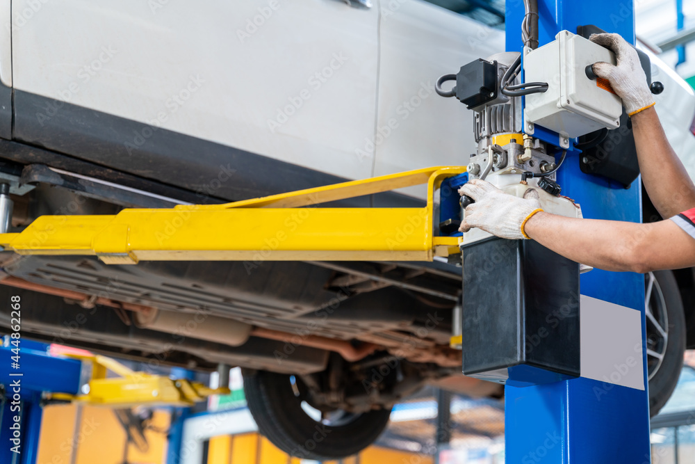 hand of auto mechanic using a car lift in car repair service centre background. hand of auto mechanic using a car lift in car repair service centre background.