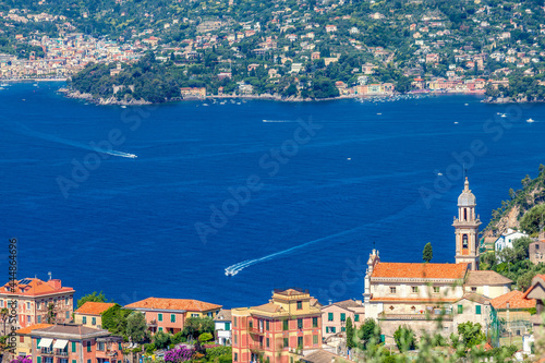 Chivari, Italy, 23 June, 2019 - View of houses of Zoagli town and Chiesa Di San Pantaleo on the foreground ang Portofino bay, Punta Pagana area on the background, view from Chiavari photo