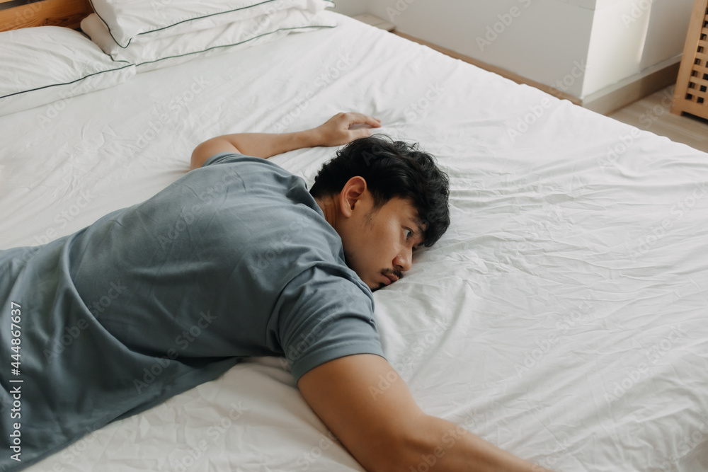 Tired Asian man is lying on the bed as he out of energy. Tired Asian man is lying on the bed as he out of energy.