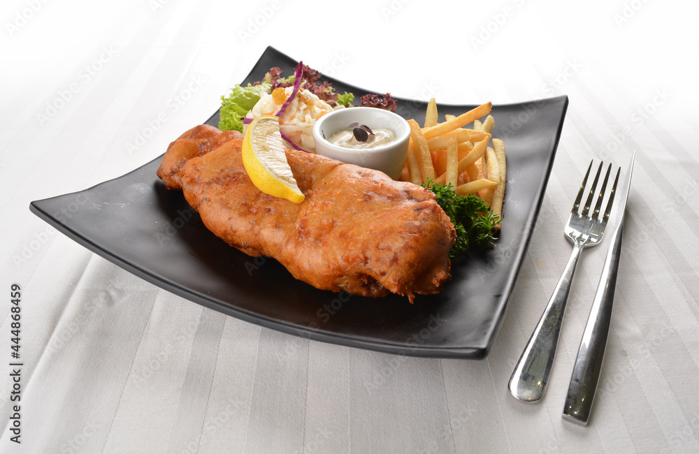 deep fried golden fish and chips with tartar sauce, lemon , French fries and salad dressing in white background western halal menu deep fried golden fish and chips with tartar sauce, lemon , French fries and salad dressing in white background western halal menu