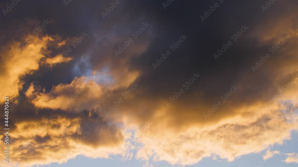 Beautiful and epic dark storm clouds with orange sunlight during sunset. Moving close up of impressive blue sky background during evening or cinematic sunrise in nature. 4K. Beautiful and epic dark storm clouds with orange sunlight during sunset. Moving close up of impressive blue sky background during evening or cinematic sunrise in nature. 4K.