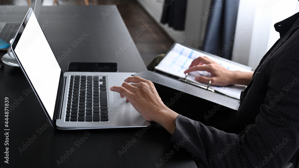 Cropped shot businessman working with laptop and reading reports in office. Cropped shot businessman working with laptop and reading reports in office.